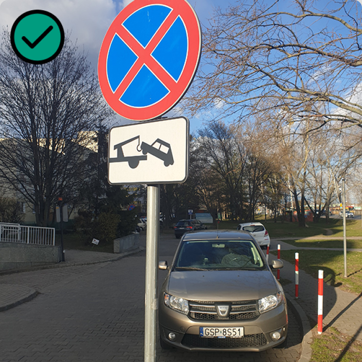 Zdjęcie pojazdu stojącego za znakiem B-36 zakaz postoju i zatrzymywania wraz z tabliczką oznaczającą odholowywanie pojazdów.